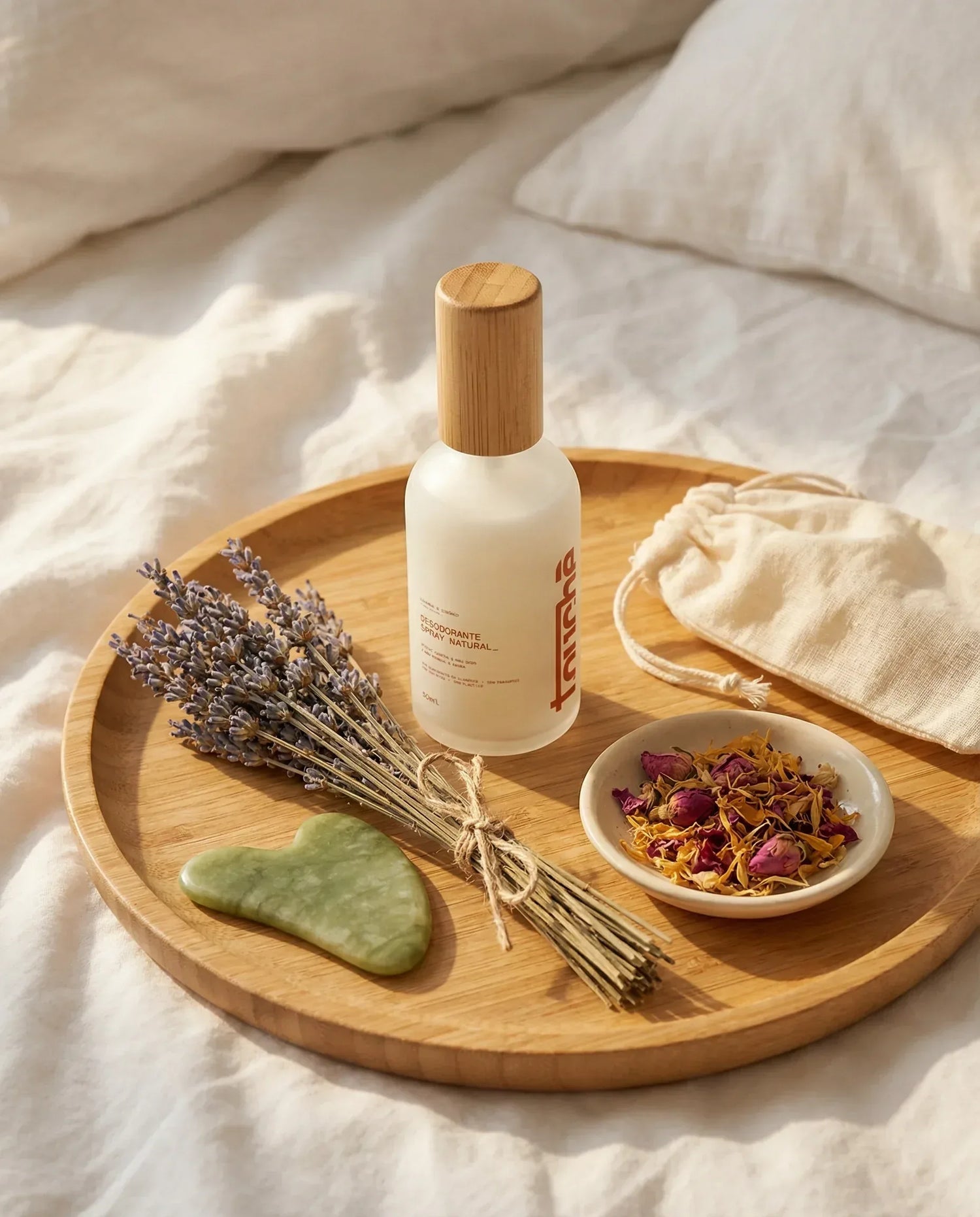 Desodorante spray natural em frasco branco com tampa de bambu, sobre bandeja de madeira com lavanda e pedra de massagem