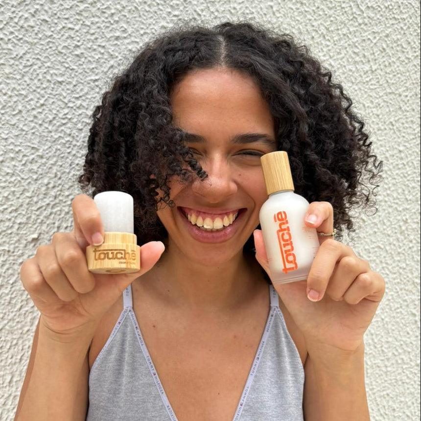 Mulher sorridente segurando desodorantes naturais com embalagem de bambu e vidro