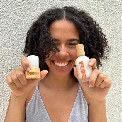 Mulher sorridente segurando desodorantes naturais com embalagem de bambu e vidro