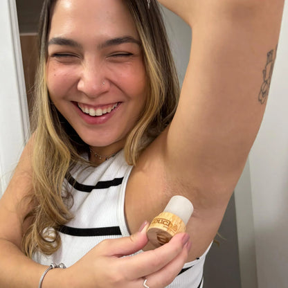Mulher sorrindo aplicando desodorante de cristal natural com embalagem de bambu